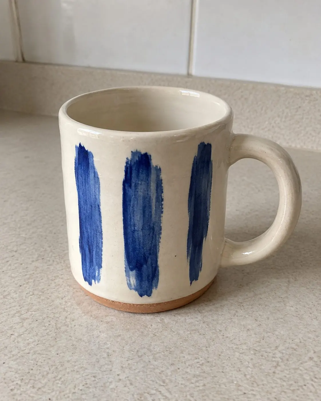 Foto de celular de uma caneca de cerâmica com pinceladas azuis